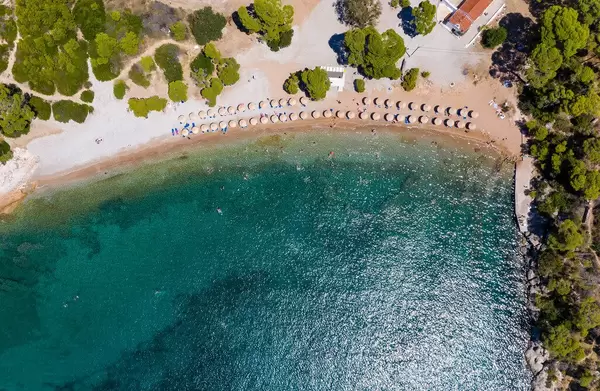 Luftaufnahme von Touristen im Urlaub und schwimmen im grünen Meer am Plaza Paraskevi-Strand in Agii Anargiri, Spetses