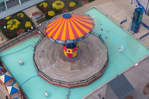 Luftaufnahme zeigt ein fahrendes, leeres Kettenkarussell in Zirkuszeltfarben