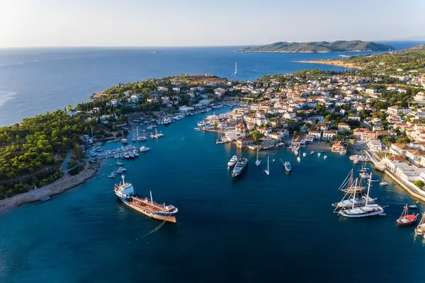 Luftaufnahme zeigt ein geankertes Frachtschiff und Segelboote im alten Hafen der Argosaronischen Insel Spetses, Griechenland, südlich von Piräus