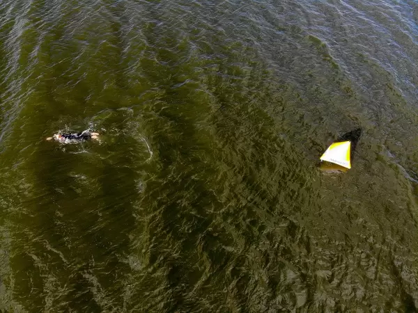 Luftaufnahme zeigt einen Sportler beim Einschwimmen für den Sportwettkampf "Ironman 70.3" in Lahti, Finnland, neben einer Boje im See Vesijärvi