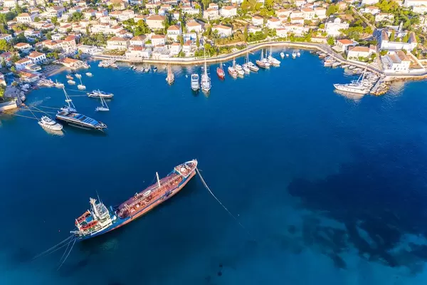 Luftbild der griechischen Insel Spetses im Sommer und einem Handelsschiff vor dem Hafen im blauen ägäischen Meer