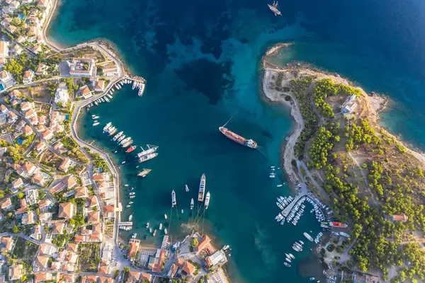Luftbild der mediterranen Insel Spetses, Griechenland, mit Küstenweg und Ankerplatz im Argolischen Golf und der Kirche Agios Nikolaos
