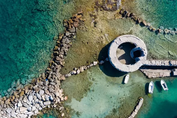 Luftbild einer venezianischen Burgruine mit Turm im Mittelmeer, vor der Hafenstadt Naoussa auf der griechischen Insel Paros