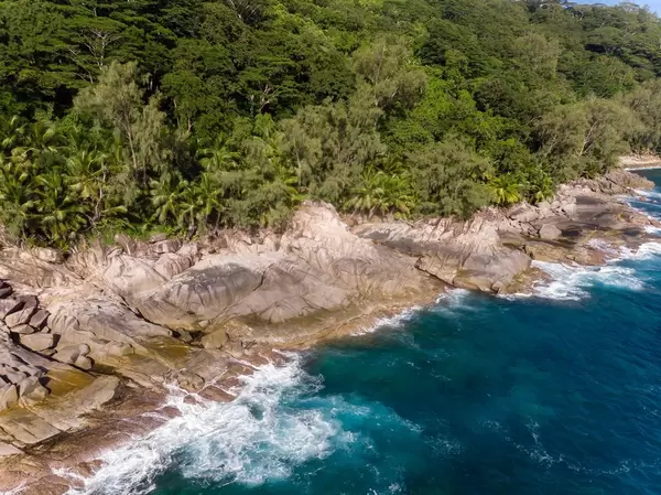 Luftbild eines blauen Ozeans und Felsenküste am Anse des Anglais im Constance Ephelia Resort auf Mahé, Seychellen
