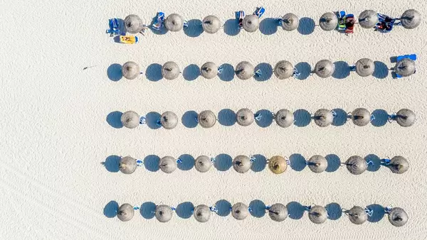 Luftbild: Fünf Reihen Sonnenschirmen werfen ihren Schatten auf den Sand. Cala Mesquida, Mallorca