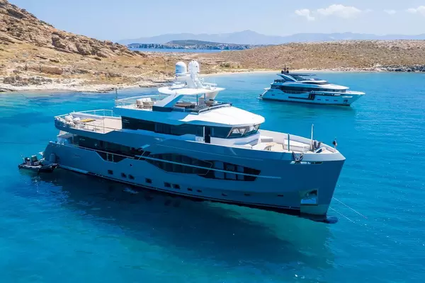 Luftbild und Nahaufnahme einer mehrstöckigen Yacht Q.M., designt von Can Yalman mit Sonnendeck vor der Felsenküste am Strand Tourkou Ammos auf Paros