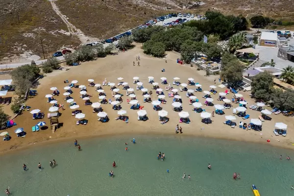 Luftbild vom Monastiri Sandtrand, mit Sonnenliegen und Sonnenschirmen an der Küste von Paros