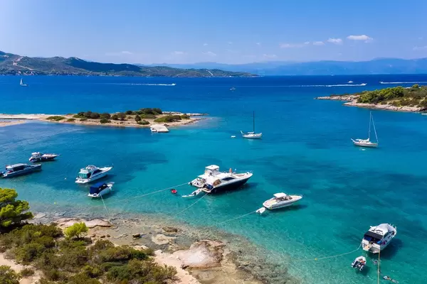 Luftbild von teuren Yachten und Urlaubern auf Motorsportbooten im blauen Meer des Argolischen Golfs vor Ermionida, Griechenland