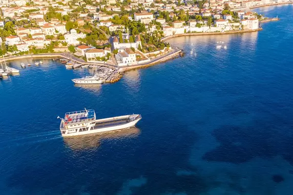 Luftbild zeigt ein Frachtschiff beim Verlassen des Hafens von Spetses, auf dem blauen Argolischen Golf in der Ägäis