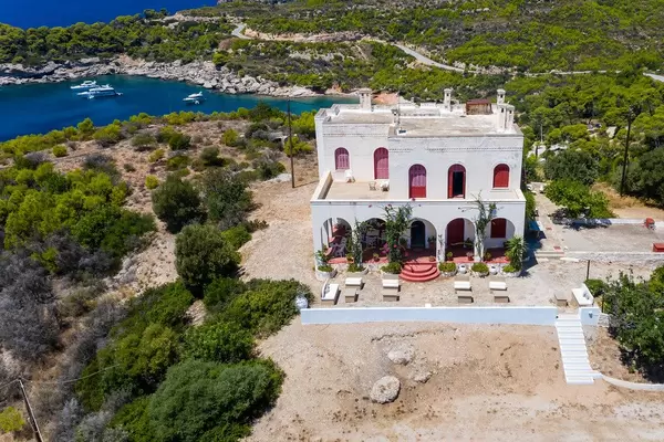 Luftbild zeigt ein mediterranes Wohnhaus auf der felsigen Insel Spetses, mit Blick auf den Strand Plaza Paraskevi