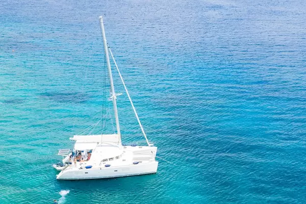 Luftbild zeigt eine Familie mit Kindern beim Urlaub auf einem Katamaran, im blauen Meer des Argolischen Golfs