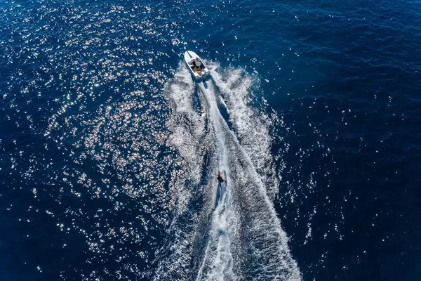 Luftbild zeigt einen Mann beim Wasserskifahren, auf dem dunkelblauen Meer