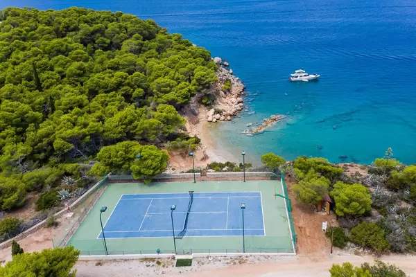 Luftbild zeigt einen Tennisplatz am Zogeriastrand an der Felsenküste der Insel Spetses, Griechenland