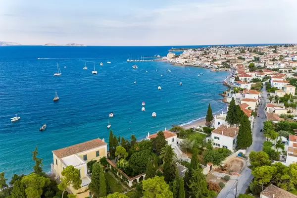 Luftbild zeigt Schiffe vor der griechischen Insel Spetses und griechische Kalksteinhäuser am Kaiki Strandweg