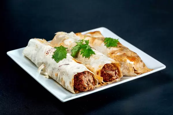 Lula Kebab in pita bread with arugula on a black background