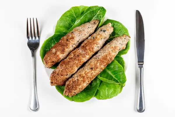 Lula kebab with romaine lettuce on a white plate, top view