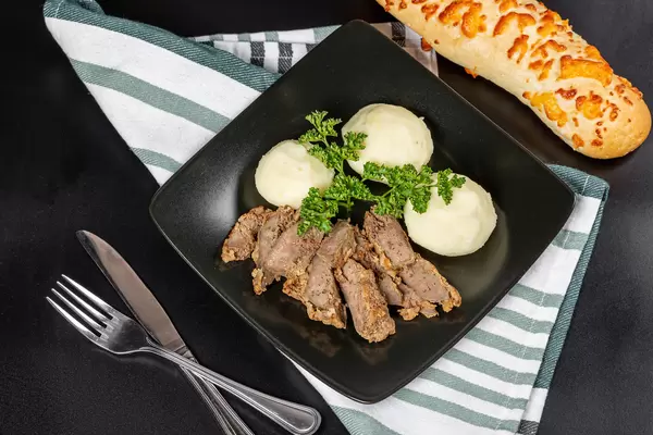Lunch background with liver slices, potato balls and cheese baguette, top view