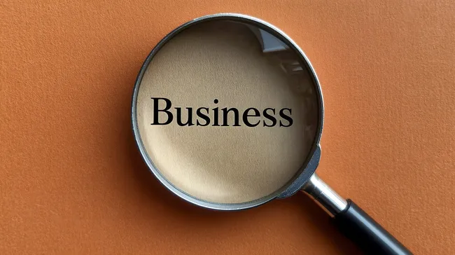 Lupe auf dem Wort 'Business' vor orangem Hintergrund