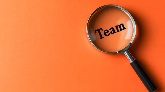 Lupe fokussiert auf das Wort 'Team' - Konzept der Teamarbeit