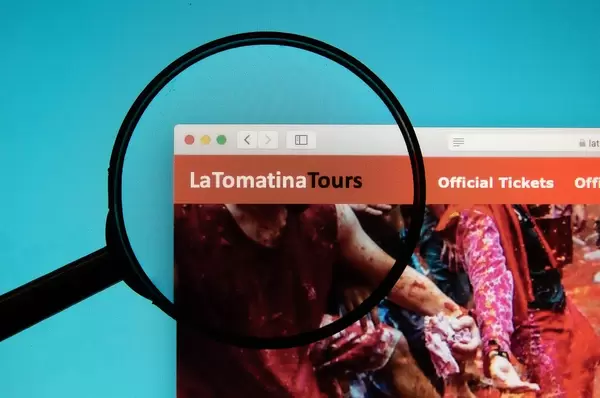Lupe hebt Logo von La Tomatina Tours auf Internetseite hervor
