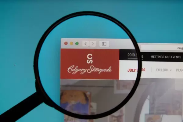 Lupe über dem Logo der Internetseite von Calgary Stampede