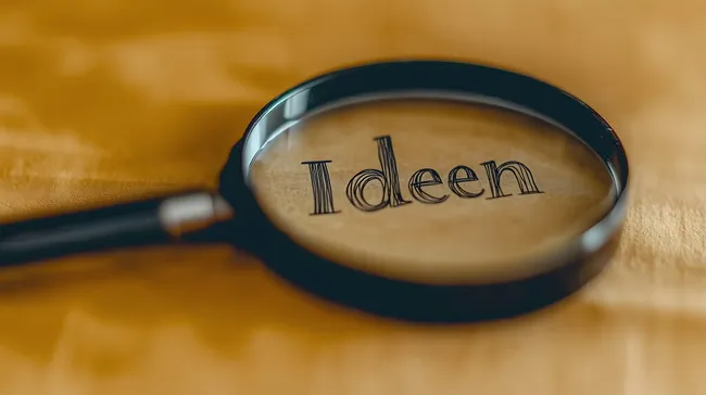 Lupe vergrößert das Wort 'Ideen' auf goldenem Hintergrund