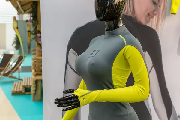 Lycra für Surfer oder Schwimmer in gelb und grau auf Puppe vor Werbeplakat