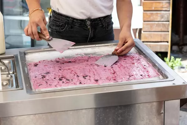 Mädchen beim Zubereiten von Eiscreme-Rollen nach thailändischer Art