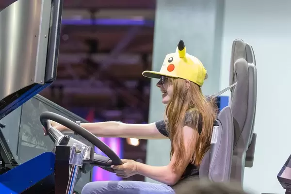 Mädchen mit Pikachumütze spielt den American Truck Simulator mit großem Lenkrad, auf der Videospielmesse Gamescom