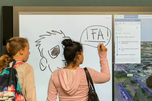 Mädchen schreibt auf einem großen Touchscreen mit Stylus-Unterstützung von Steelcase