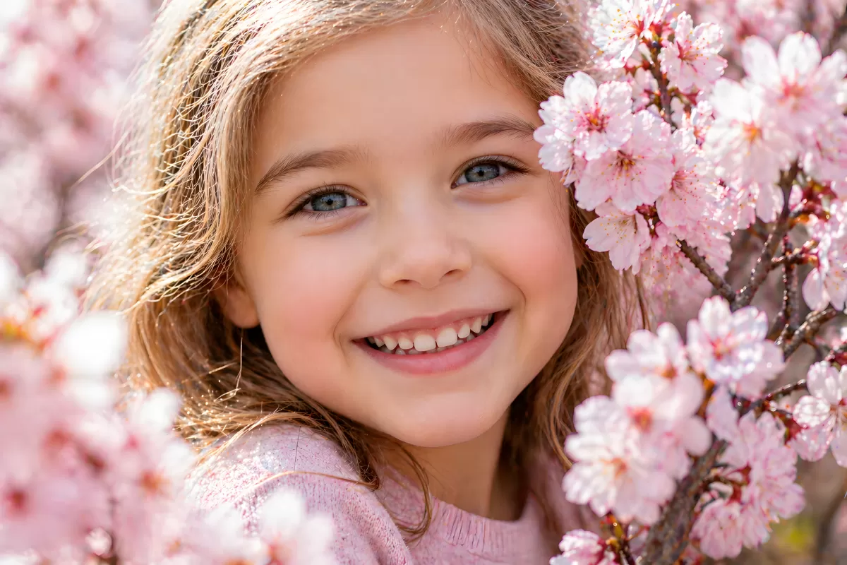 Mädchen lacht zwischen rosa Kirschblüten im Frühling