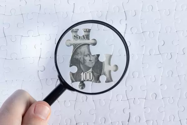 Magnifier and white puzzle on hundred dollars banknotes