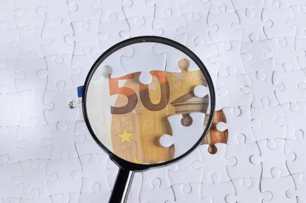 Magnifying glass over missing puzzle 50 Euro banknote