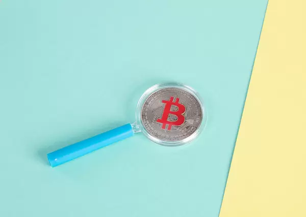 Magnifying glass over sIlver Bitcoin coin