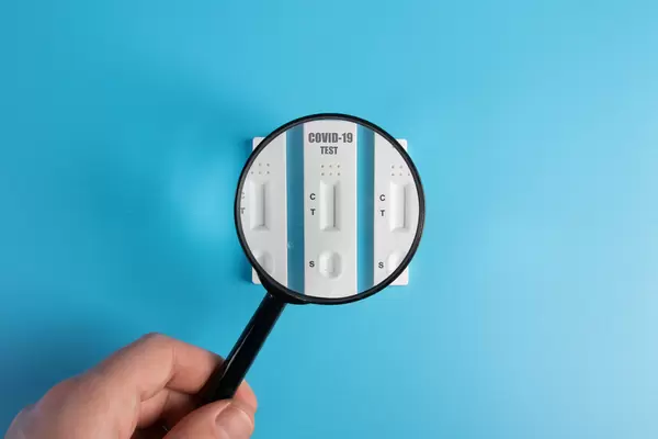 Magnifying glass over test kits for viral disease COVID-19