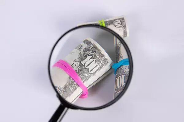 Magnifying glass over US dollar bills in rolls