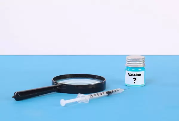 Magnifying glass, syringe and Syringe and bottle with blue fluid and Vaccine text