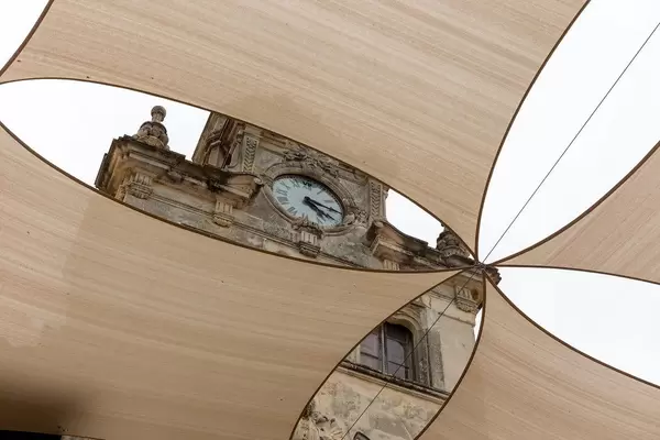 Majorca: the clock on the facade of the Alcudía town hall, framed by large square shade sails