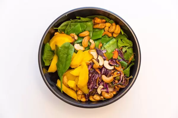 MaKE. Salate Bowls und Suppen - Indian Summer Bowl mit Blattspinat, Zuckerschoten, warme Rosmarin Kartoffeln, Rohkostsalat, geröstete gelbe Karotten, Cashews, Basilikum, Koriander sowie gelbe Thai-Curry Sauce
