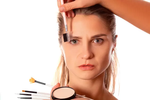 Makeup artist combing a woman's eyebrows with a brush