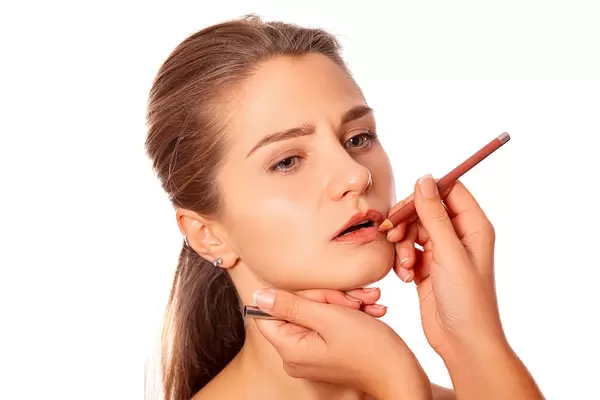 Makeup artist paints lips with lip pencil