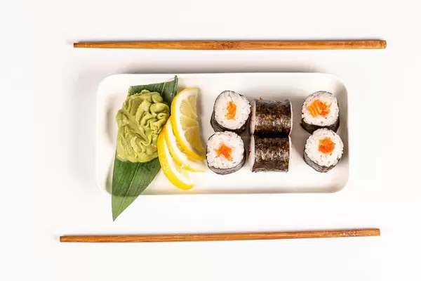 Maki rolls with salmon and chopsticks on white, top view