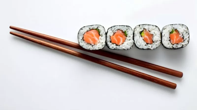 Maki Sushi mit Lachsfüllung und Essstäbchen auf Weiß