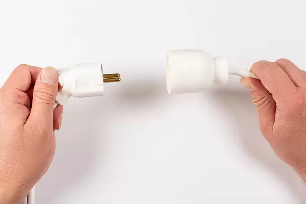 Male hand puts plug in the socket, white background