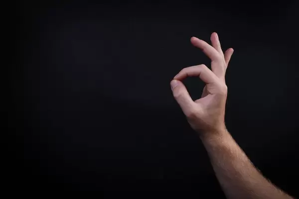 Male hand shows gesture OK on black background