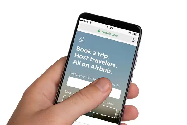 Male hands holding smartphone with an open Airbnb application