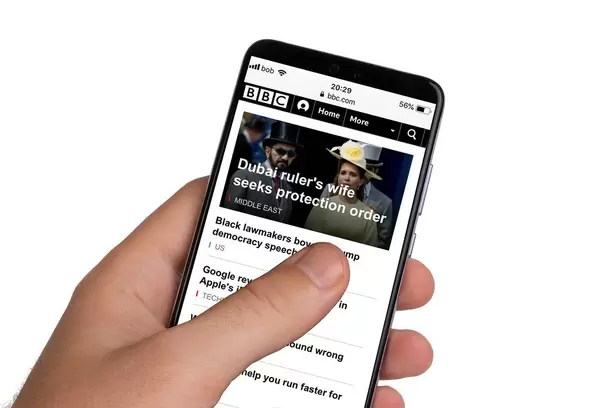 Male hands holding smartphone with an open BBC News application