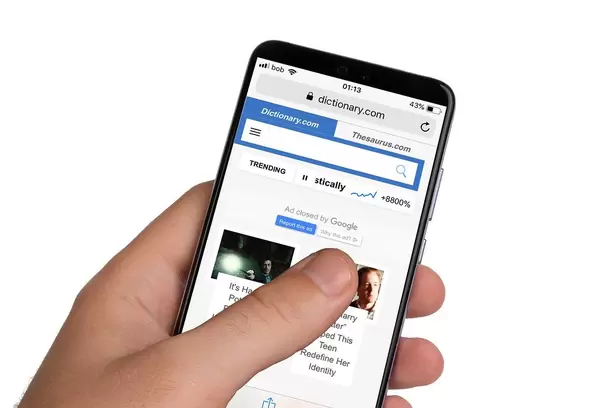 Male hands holding smartphone with an open Dictionary.com website