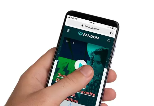 Male hands holding smartphone with an open Fandom website