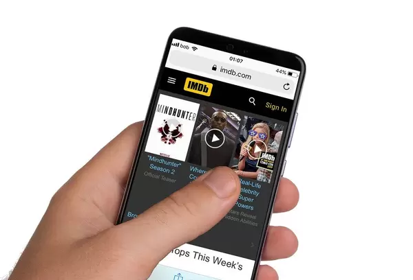 Male hands holding smartphone with an open IMDb website